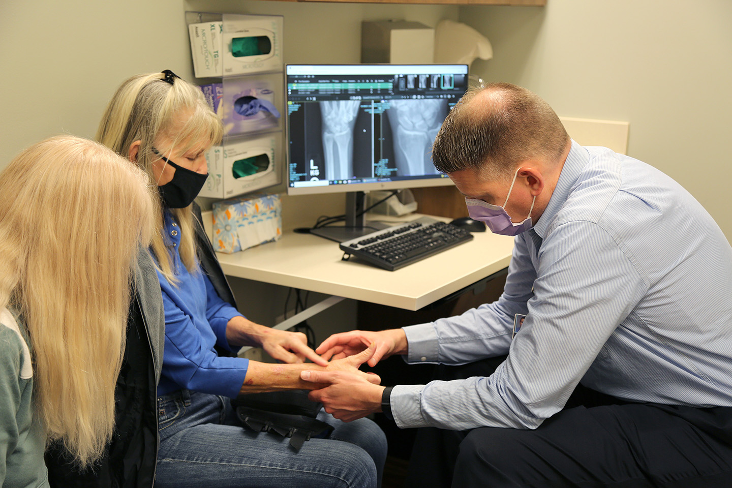 Brett Clayton, PA-C, examines a female patient's wrist.