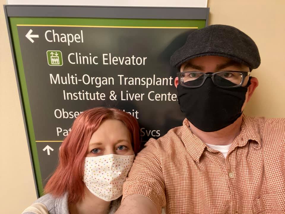 Woman and man in mask next to organ transplant sign