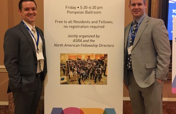 medical students stand next to ASRA conference poster