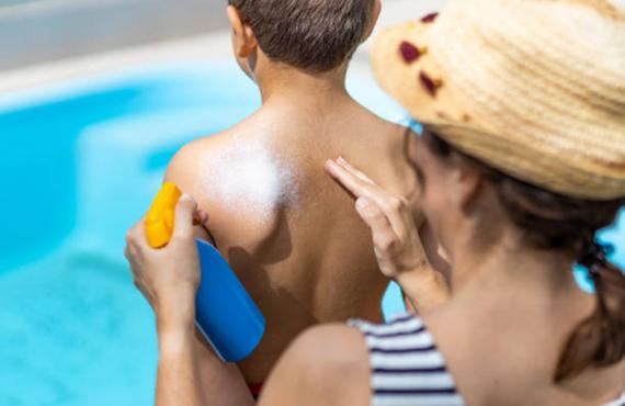 Woman putting sunscreen on boy's back Woman putting sunscreen on boy's back