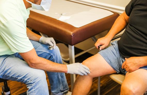 Orthopedic surgeon examines patient's knee Orthopedic surgeon examines patient's knee